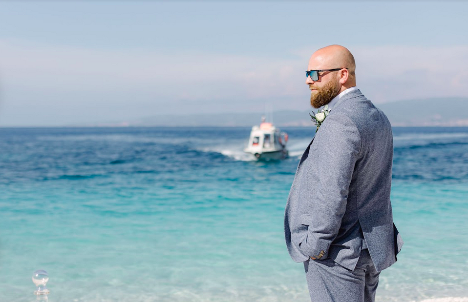 Mann im Anzug blickt aufs Meer, Motorboot im Hintergrund