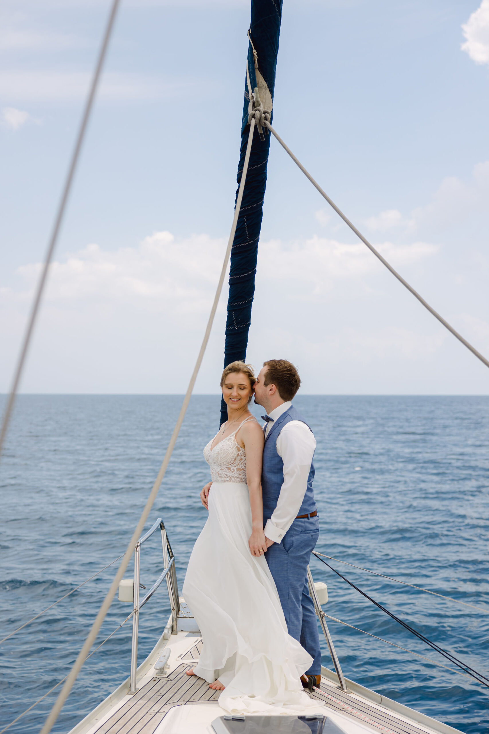 Hochzeitspaar steht auf einem Segelboot im Meer