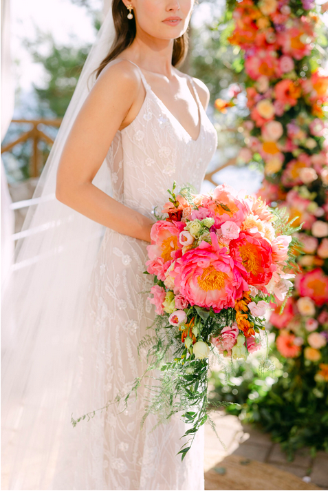 Braut mit Blumenstrauß vor Blumengirlande